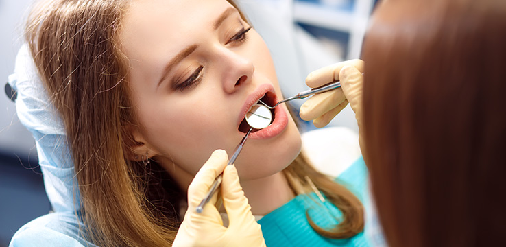 young woman getting her teeth examined by a dentist