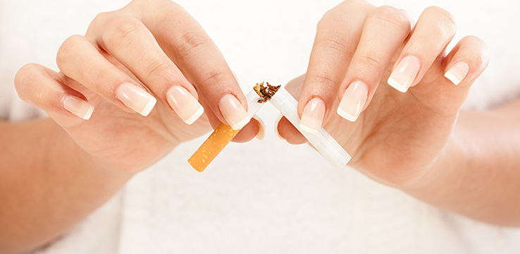 the hands of a woman breaking a cigarette in half