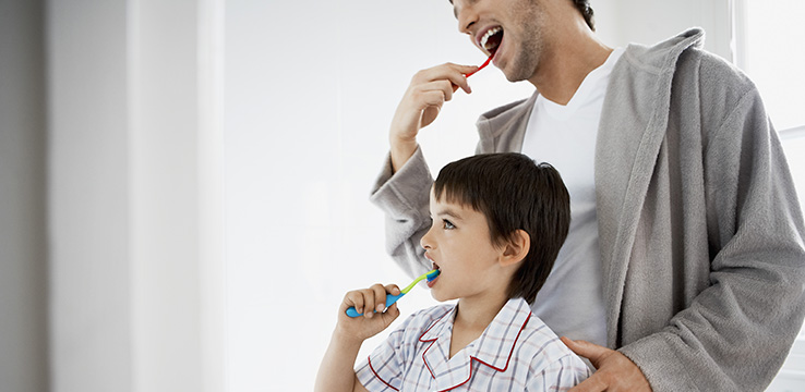 father and son brushing their teeth together