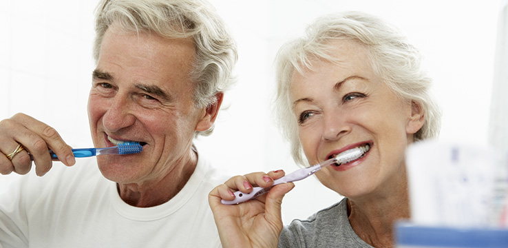 elderly couple brushing their teeth together they look happy