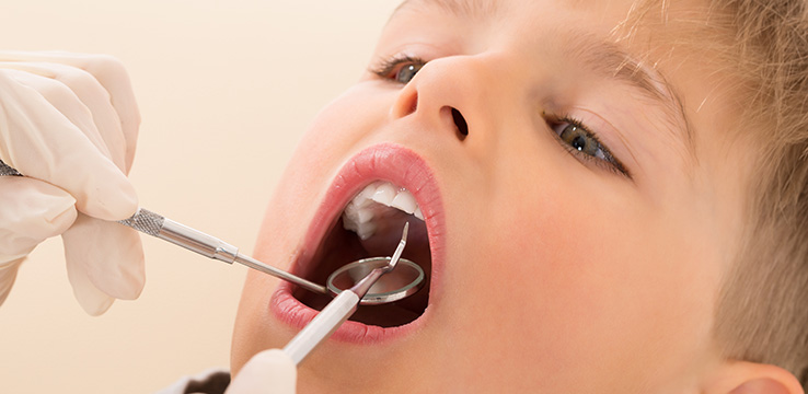 little boy with dental tools being used in his mouth