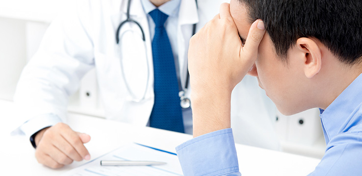 man with his hands on the forehead talking with a dentist.