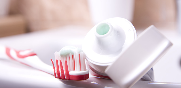 tube of tooth paste with the lid off and a toothbrush with toothpaste on it